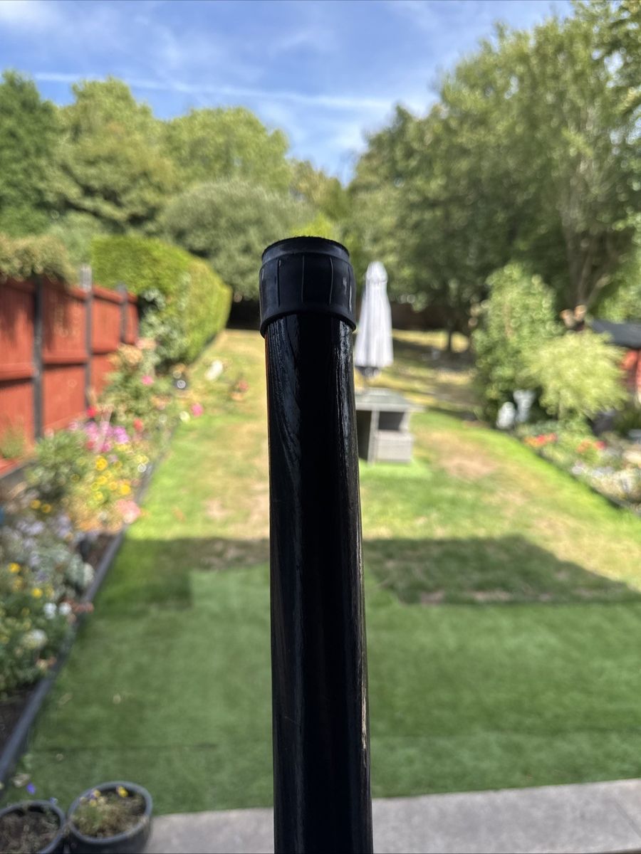 A black finish pole stood in a garden