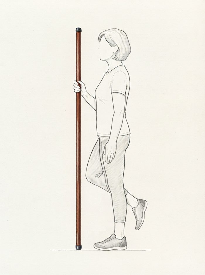 Standing on one leg with the pole for support